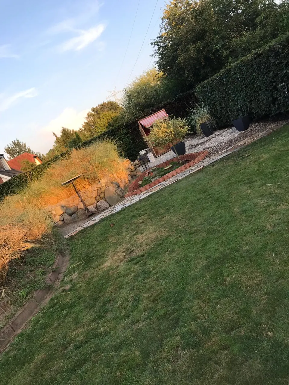 Gartenanlage mit Natursteinmauer, Ziergräsern und Kiesweg in Kiel