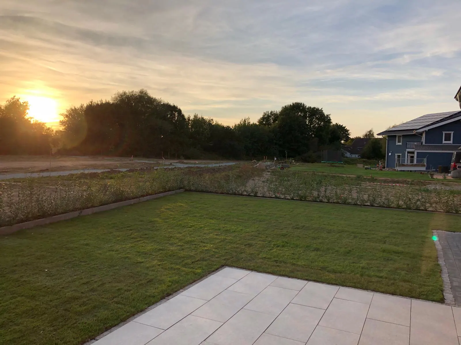 Neu angelegter Rasen mit Betonrandsteinen bei Sonnenuntergang