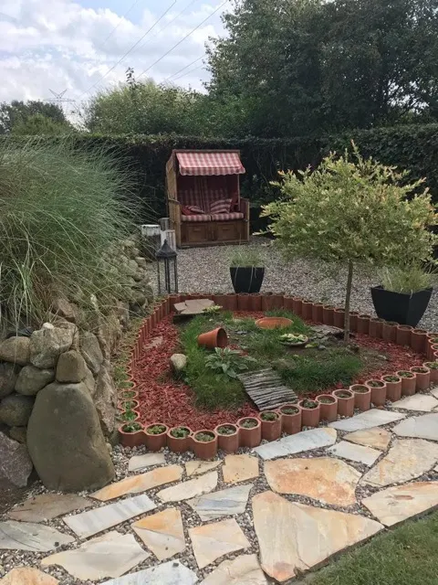 Sitzecke mit Strandkorb und rundem Mulchbeet im gepflegten Garten
