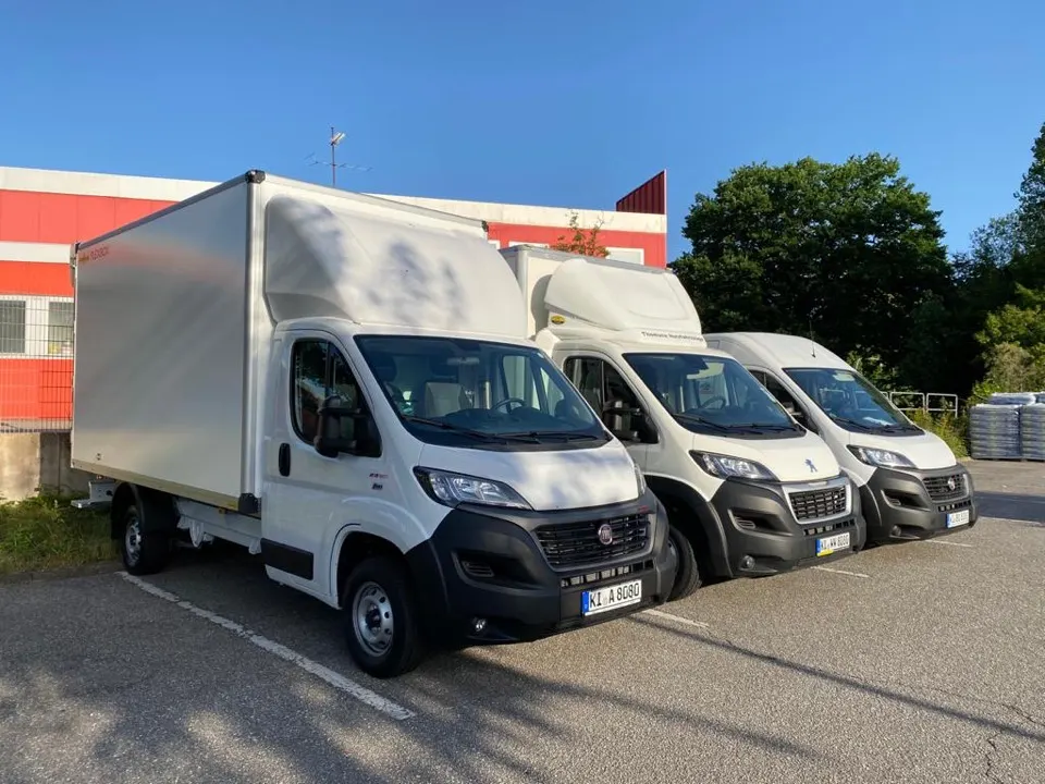 Fuhrpark mit drei Transportern vor dem Betriebsgebäude